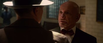 Movie still from “Shutter Island” (2010), directed by Martin Scorsese – A man in a suit and a bow tie talking to another man in a hat; Close Up shot, Over the shoulder angle
