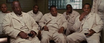 Movie still from “Shutter Island” (2010), directed by Martin Scorsese – A group of men in white suits sitting in a room; Medium shot, High angle
