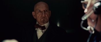 Movie still from “Shutter Island” (2010), directed by Martin Scorsese – A man with a bald head wearing a suit and bow tie; Close Up shot, Low angle