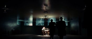 Movie still from “Shutter Island” (2010), directed by Martin Scorsese – Two men are standing in a dimly - lit room; Wide shot, Low angle