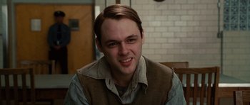 Movie still from “Shutter Island” (2010), directed by Martin Scorsese – A man with a brown vest smiling for the camera; Close Up shot, Over the shoulder angle