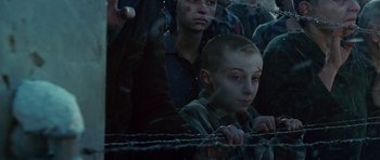 Movie still from “Shutter Island” (2010), directed by Martin Scorsese – A young boy is sitting behind a barbed wire fence; Close Up shot, High angle