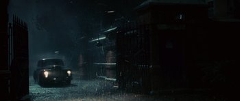 Movie still from “Shutter Island” (2010), directed by Martin Scorsese – A person is walking in the rain near a fence; Extreme Wide shot, High angle