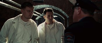 Movie still from “Shutter Island” (2010), directed by Martin Scorsese – A man in a white jacket standing next to another man in a white jacket; Medium shot, Low angle