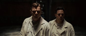 Movie still from “Shutter Island” (2010), directed by Martin Scorsese – A man in a trench coat standing next to another man; Medium shot, Low angle