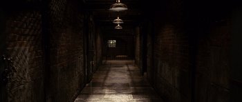 Movie still from “Shutter Island” (2010), directed by Martin Scorsese – A dark hallway with lights hanging from the ceiling; Extreme Wide shot, High angle