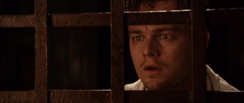 Movie still from “Shutter Island” (2010), directed by Martin Scorsese – A person behind a metal fence; Close Up shot, Low angle