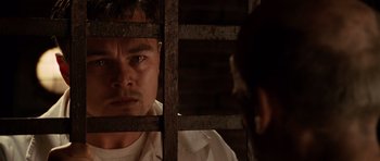 Movie still from “Shutter Island” (2010), directed by Martin Scorsese – A man looking through bars of a jail cell; Close Up shot, Low angle