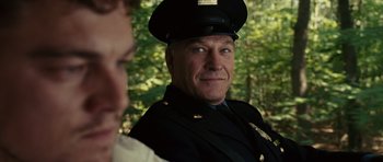 Movie still from “Shutter Island” (2010), directed by Martin Scorsese – A man in a police officer's uniform looks into the camera; Close Up shot, Over the shoulder angle
