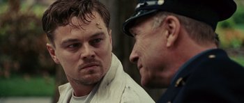 Movie still from “Shutter Island” (2010), directed by Martin Scorsese – A man and a man in a police uniform talking to each other; Close Up shot, Over the shoulder angle