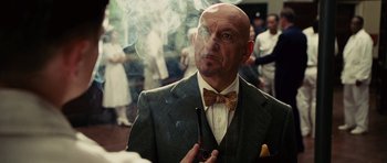 Movie still from “Shutter Island” (2010), directed by Martin Scorsese – A man in a suit and bow tie smoking a pipe; Close Up shot, Over the shoulder angle