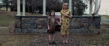 Movie still from “Shutter Island” (2010), directed by Martin Scorsese – Two people standing next to each other in front of a car; Wide shot, Low angle