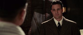 Movie still from “Shutter Island” (2010), directed by Martin Scorsese – A man wearing a suit and tie standing in front of a brick wall; Close Up shot, Over the shoulder angle