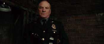 Movie still from “Shutter Island” (2010), directed by Martin Scorsese – A man in a police uniform stands in front of a brick wall; Close Up shot, Low angle