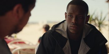 Movie still from “Top Boy” (2011), created by Ronan Bennett – A young man is looking at the camera while standing next to another man; Close Up shot, Over the shoulder angle