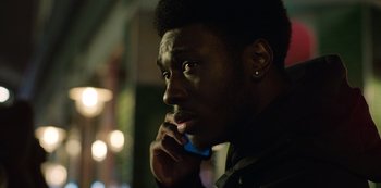 Movie still from “Top Boy” (2011), created by Ronan Bennett – A person talking on a cell phone; Close Up shot, Low angle