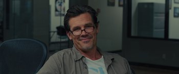 Movie still from “Sicario” (2015), directed by Denis Villeneuve – A person wearing glasses and smiling; Close Up shot, Over the shoulder angle