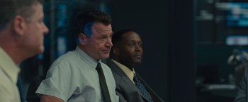 Movie still from “Sicario” (2015), directed by Denis Villeneuve – Two men in business suits sitting next to each other; Close Up shot, Over the shoulder angle