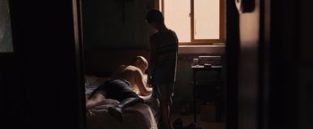 Movie still from “Sicario” (2015), directed by Denis Villeneuve – A man laying on top of a bed next to a boy; Medium shot, High angle