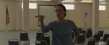 Movie still from “Sicario” (2015), directed by Denis Villeneuve – A woman is pointing to something in a room; Medium shot, Over the shoulder angle