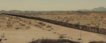 Movie still from “Sicario” (2015), directed by Denis Villeneuve – A view of the border fence in the middle of the desert; Extreme Wide shot, High angle
