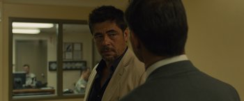 Movie still from “Sicario” (2015), directed by Denis Villeneuve – A man in a suit and tie looking into a mirror; Close Up shot, Over the shoulder angle