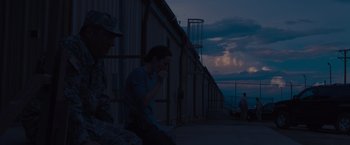 Movie still from “Sicario” (2015), directed by Denis Villeneuve – A man sitting on the side of a building at night; Wide shot, Over the shoulder angle