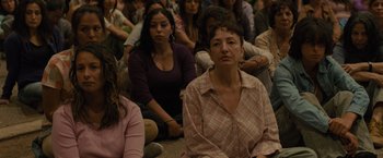 Movie still from “Sicario” (2015), directed by Denis Villeneuve – A group of people sitting on the ground in front of a building; Medium shot, High angle