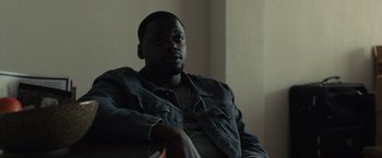 Movie still from “Sicario” (2015), directed by Denis Villeneuve – A man sitting in a chair with a book in his hand; Close Up shot, Over the shoulder angle