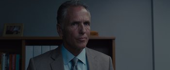 Movie still from “Sicario” (2015), directed by Denis Villeneuve – A man in a suit and tie in front of a book case; Close Up shot, Over the shoulder angle