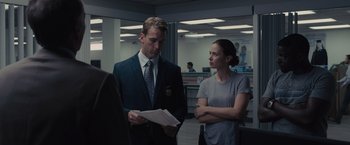 Movie still from “Sicario” (2015), directed by Denis Villeneuve – A man and a woman standing next to each other in an office; Medium shot, Over the shoulder angle