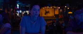 Movie still from “Sicario” (2015), directed by Denis Villeneuve – A woman sitting at a table in front of a neon sign at night; Close Up shot, Over the shoulder angle