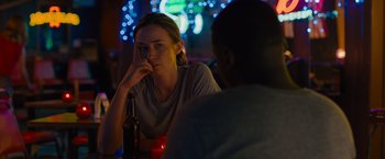 Movie still from “Sicario” (2015), directed by Denis Villeneuve – A woman sitting at a table with a glass of beer; Close Up shot, Over the shoulder angle