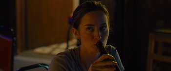 Movie still from “Sicario” (2015), directed by Denis Villeneuve – A woman drinking a beer in a dark room; Close Up shot, Over the shoulder angle