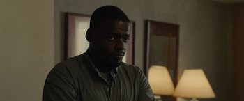 Movie still from “Sicario” (2015), directed by Denis Villeneuve – A man sitting in front of a lamp in a dark room; Close Up shot, Over the shoulder angle