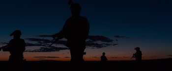 Movie still from “Sicario” (2015), directed by Denis Villeneuve – A person sitting on a hill at sunset; Wide shot, Low angle
