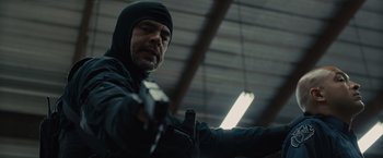 Movie still from “Sicario” (2015), directed by Denis Villeneuve – A man holding a gun while wearing a black jacket; Close Up shot, Low angle