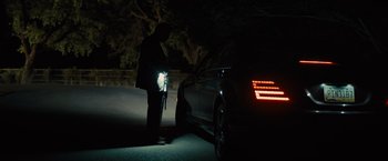Movie still from “Sicario” (2015), directed by Denis Villeneuve – A person standing next to a car at night; Wide shot, Low angle