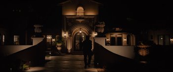 Movie still from “Sicario” (2015), directed by Denis Villeneuve – A man walking down the sidewalk in front of a building; Extreme Wide shot, Low angle