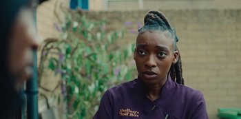 Movie still from “Top Boy” (2011), created by Ronan Bennett – A person with a purple shirt and a purple jacket; Close Up shot, Over the shoulder angle