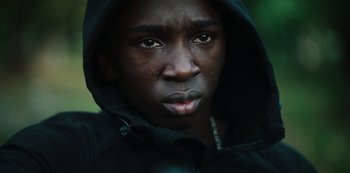 Movie still from “Top Boy” (2011), created by Ronan Bennett – A person wearing a hooded jacket; Close Up shot, High angle