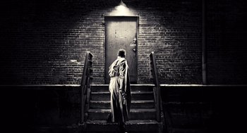 Movie still from “Sin City” (2005), directed by Frank Miller – A person walking up some stairs in front of a door; Wide shot, Low angle