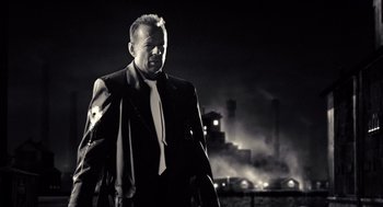 Movie still from “Sin City” (2005), directed by Frank Miller – A black and white photo of a man in a suit and tie; Medium shot, Low angle