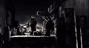 Movie still from “Sin City” (2005), directed by Frank Miller – A man is standing over another man on a dock; Wide shot, High angle