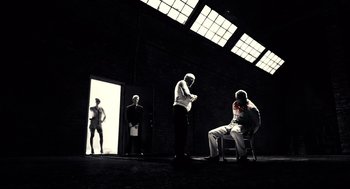 Movie still from “Sin City” (2005), directed by Frank Miller – A group of people standing in a room; Wide shot, Low angle