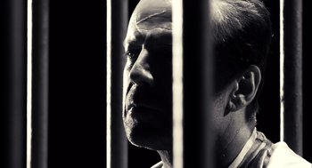 Movie still from “Sin City” (2005), directed by Frank Miller – A black and white photo of a man behind bars; Close Up shot, Low angle