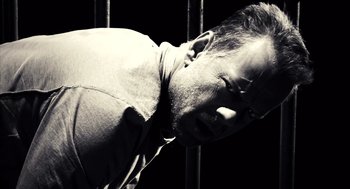 Movie still from “Sin City” (2005), directed by Frank Miller – A black and white photo of a man in a prison cell; Close Up shot, Overhead angle
