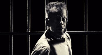 Movie still from “Sin City” (2005), directed by Frank Miller – A black and white photo of a man in a jail cell; Close Up shot, High angle