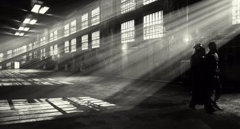Movie still from “Sin City” (2005), directed by Frank Miller – The sun is shining through the windows of an industrial building; Extreme Wide shot, Low angle