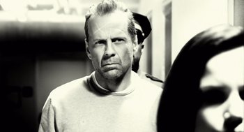 Movie still from “Sin City” (2005), directed by Frank Miller – Black and white photograph of a man in a white shirt; Close Up shot, Over the shoulder angle